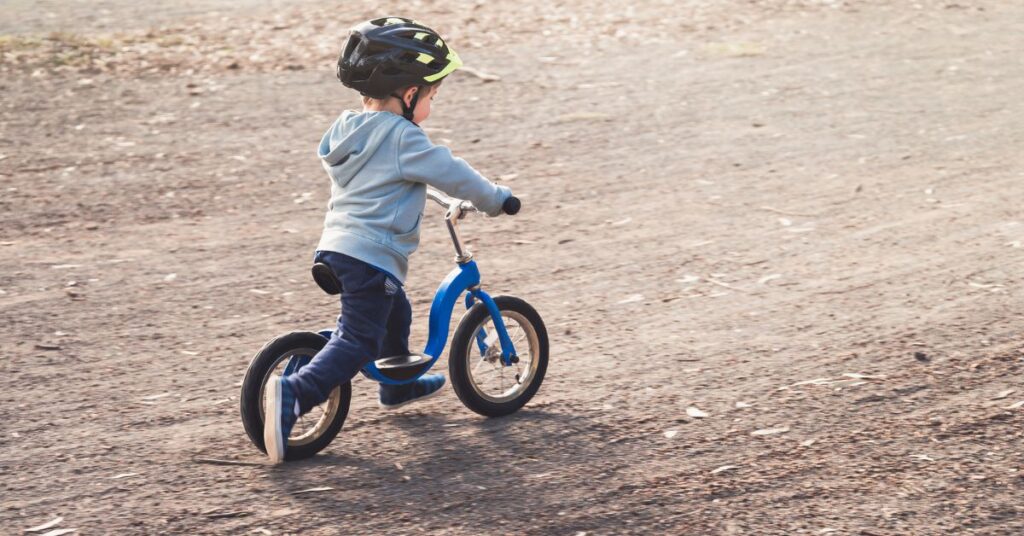 Lille dreng kører på en blå løbecykel